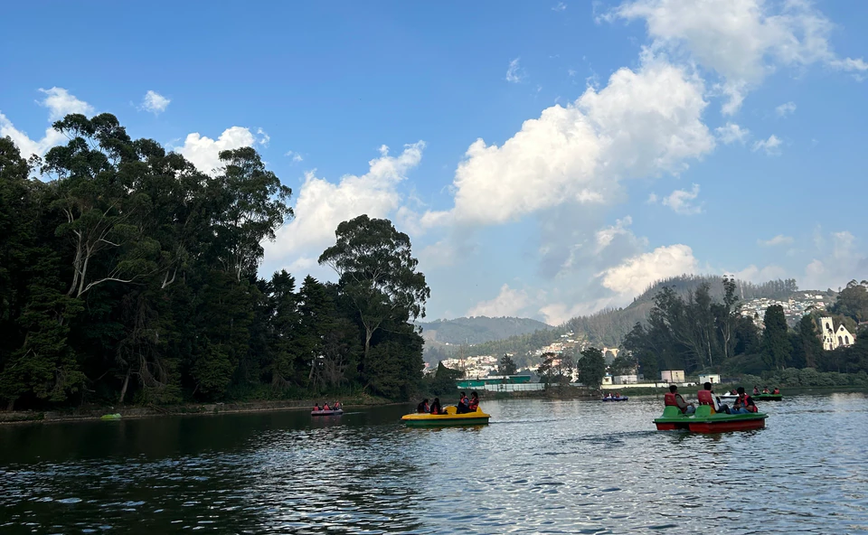 Boats on a lake surrounded by wooded hills, photographed by Sumit